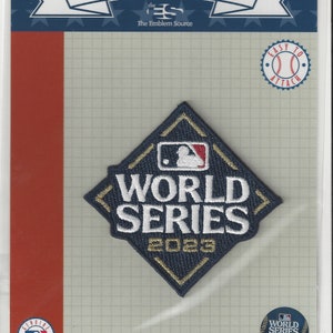 Può includere: Un cerotto a forma di diamante blu e oro con il testo "World Series 2023" e un logo di baseball. Il cerotto è confezionato in un sacchetto di plastica trasparente con un'intestazione bianca che recita "MLB Fanpatch™ The Emblem Source".