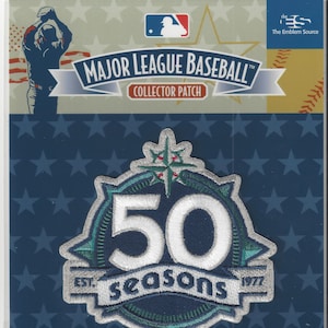 May include: A Major League Baseball collector patch commemorating 50 seasons. The patch features a large "50" in white, surrounded by teal and silver embroidery, with "seasons" and "1977" below. The background is navy blue with white stars.