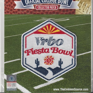 May include: A collector's patch for the Vrbo Fiesta Bowl, featuring a white, red, and blue design with the text "Vrbo Fiesta Bowl." The patch is in a clear plastic package, with a football and a football field in the background.