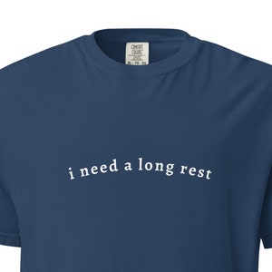Puede incluir: Una camiseta azul marino con el texto "i need a long rest" impreso en blanco en la parte delantera.