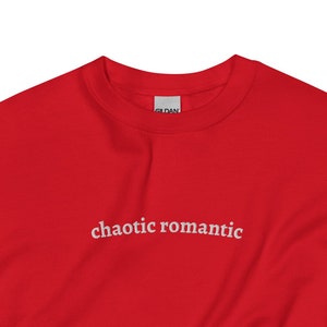 May include: Red sweatshirt with the text "chaotic romantic" in white lettering.