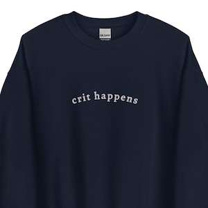以下が含まれることがあります： 紺色のスウェットシャツに白い文字で「crit happens」と書かれています。