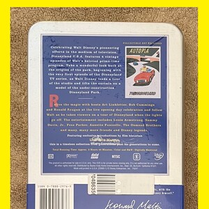 K&ouml;nnte beinhalten: Eine silberne Blechdose mit einem blauen und wei&szlig;en Bild eines roten Autos, das durch eine futuristische Stadt f&auml;hrt. Der Text "Autopia" und "Tomorrowland" ist auf dem Bild zu sehen. Die Dose enth&auml;lt eine DVD der Fernsehserie Disneyland U.S.A. Der Text "Celebrating Walt Disney's pioneering efforts in the medium of television, Disneyland U.S.A. features 4 vintage episodes of Walt's beloved prime-time program." ist auf der Dose zu sehen.