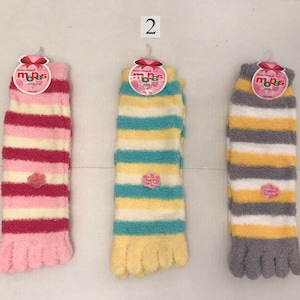 May include: Three pairs of fuzzy striped socks with toe separators. The socks are pink and white, blue and white, and gray and white.