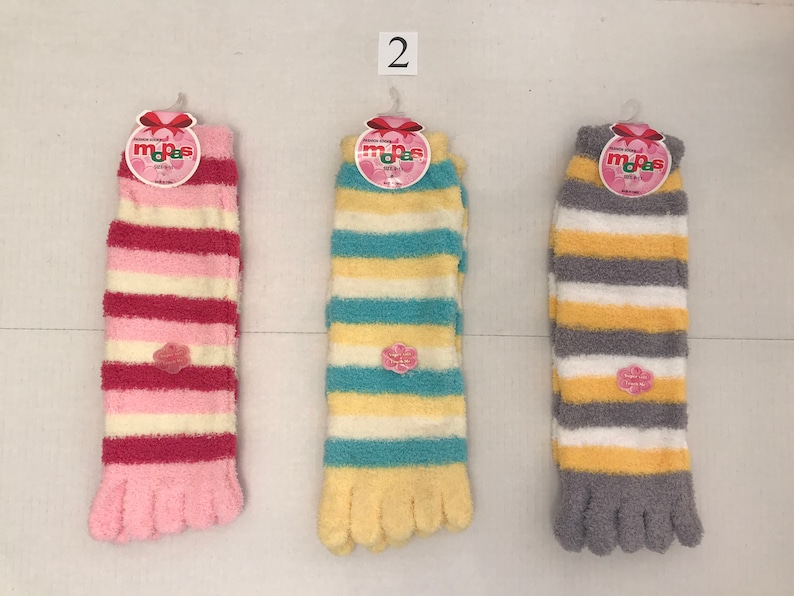 May include: Three pairs of fuzzy striped socks with toe separators. The socks are pink and white, blue and white, and gray and white.