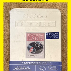 K&ouml;nnte beinhalten: Ein wei&szlig;es DVD-Geh&auml;use aus Metall mit einem blauen und wei&szlig;en Etikett, das eine Weltraum-Illustration mit einer Rakete und Astronauten zeigt. Das Etikett lautet "Tomorrow Land: Disney im Weltraum und dar&uuml;ber hinaus". Das Geh&auml;use ist Teil einer limitierten Serie von Walt Disney Treasures.