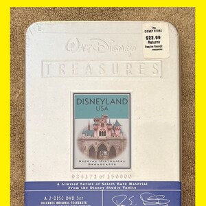 K&ouml;nnte beinhalten: Ein silbernes DVD-Geh&auml;use mit einem wei&szlig;en Etikett, das ein Bild von Dornr&ouml;schens Schloss in Disneyland zeigt. Das Etikett lautet "Walt Disney Treasures Disneyland USA Special Historical Broadcasts" und "A Limited Series of Select Rare Material from the Disney Studio Vaults". Das Geh&auml;use kostet 22,99&nbsp;&euro;.