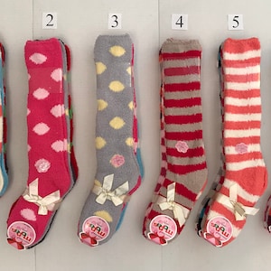May include: Six pairs of knee-high socks with different patterns. The socks are white, pink, gray, red, orange, and blue. Each pair has a small flower design on the front.