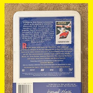 K&ouml;nnte beinhalten: Ein DVD-Geh&auml;use mit blau-wei&szlig;em Design, das ein Vintage-Bild eines Autos vor einem Geb&auml;ude mit dem Text "Autopia" und "Tomorrowland" zeigt. Das Geh&auml;use enth&auml;lt einen Sammeldruck und eine Zeitleiste von Walt Disneys Karriere von 1925 bis 2000. Der Text "Celebrating Walt Disney's pioneering efforts in the medium of television" ist ebenfalls enthalten. Die DVD tr&auml;gt den Titel "Disneyland U.S.A." und enth&auml;lt 4 Vintage-Episoden von Walts beliebtem Primetime-Programm.