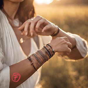 May include: A woman's wrist adorned with a stack of colorful bracelets, featuring a variety of textures and materials, including leather, string, and beads. The bracelets are layered and tied together, creating a bohemian and stylish look.
