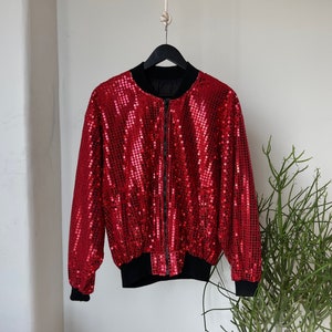 Può includere: Una giacca bomber rossa con paillettes, cerniera nera e polsini e vita a costine.