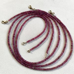 Puede incluir: Múltiples hilos de collares de piedras preciosas de rubí. Cada collar está compuesto por pequeñas gemas rosas oscuras de corte cuadrado. Los collares tienen cierres plateados. Las piedras preciosas son de un color rosa intenso y rico.