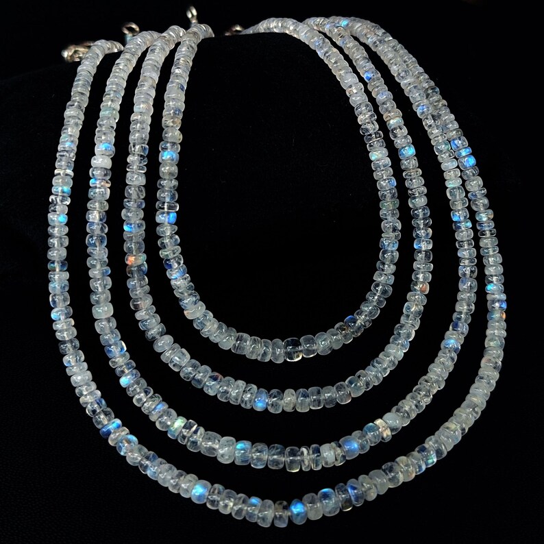 Puede incluir: Cinco hilos de delicados collares, cada uno compuesto por peque&ntilde;as cuentas transl&uacute;cidas con sutiles tonos azules y blancos. Los collares se exhiben sobre un fondo negro, resaltando su calidad brillante. Las cuentas parecen ser de tama&ntilde;o uniforme y est&aacute;n ensartadas.
