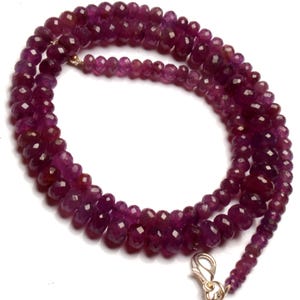 Può includere: Una collana di perle di pietre preziose viola scuro con una chiusura in argento. Le perle sono sfaccettate e hanno una forma leggermente irregolare.