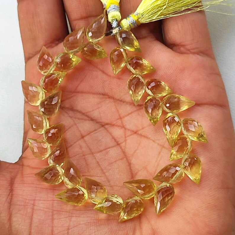 May include: A strand of yellow gemstone beads in a teardrop shape. The beads are faceted and have a translucent appearance.