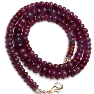 May include: A purple gemstone bead necklace with a silver clasp. The necklace is made of small, round beads that are strung together on a silver chain.