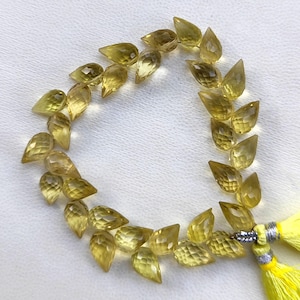 May include: A strand of 20 faceted teardrop-shaped beads made of yellow citrine. The beads are strung on a thin cord and have a tassel at the end.