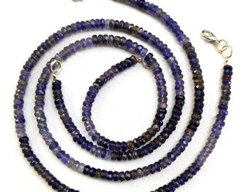 Könnte beinhalten: Eine lange Kette aus facettierten Amethystperlen in Violett- und Grautönen. Die Perlen sind auf einer silbernen Kette mit einem silbernen Verschluss aufgefädelt.