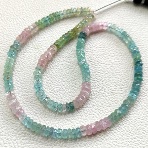 Puede incluir: Una hebra de cuentas redondas facetadas con un degradado de colores translúcidos que incluye rosa pálido, verde suave y azul claro. Las pequeñas cuentas circulares están ensartadas en un hilo fino, creando un bucle continuo y flexible.