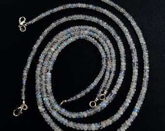 Puede incluir: Un delicado collar compuesto por pequeñas cuentas redondas e iridiscentes. Las cuentas muestran una gama de colores, incluyendo blanco, azul y toques de otros tonos. El collar presenta cierres dorados en cada extremo, sobre un fondo negro.