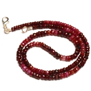 May include: A red ruby gemstone necklace with a silver clasp. The necklace is made of small, faceted beads.