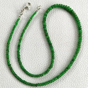May include: A necklace composed of small, round, vibrant green beads strung together. The strand features a silver-toned metal lobster claw clasp and a small jump ring at the ends, allowing for a secure closure when worn around the neck.