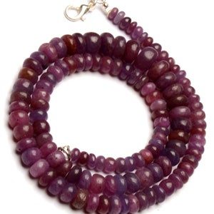 May include: A double strand necklace made of purple gemstone beads. The beads are oval shaped and have a smooth, polished finish. The necklace is secured with a silver clasp.