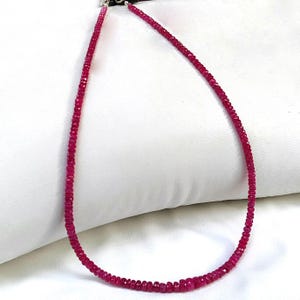 May include: A pink gemstone necklace made of small, faceted beads. The necklace is strung on a silver chain and has a clasp closure.