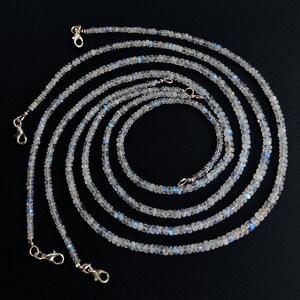 Puede incluir: M&uacute;ltiples hilos de delicados collares de cuentas con un aspecto brillante e iridiscente. Las peque&ntilde;as cuentas redondas son de un color p&aacute;lido y transl&uacute;cido con destellos azules. Cada collar est&aacute; terminado con un cierre plateado.