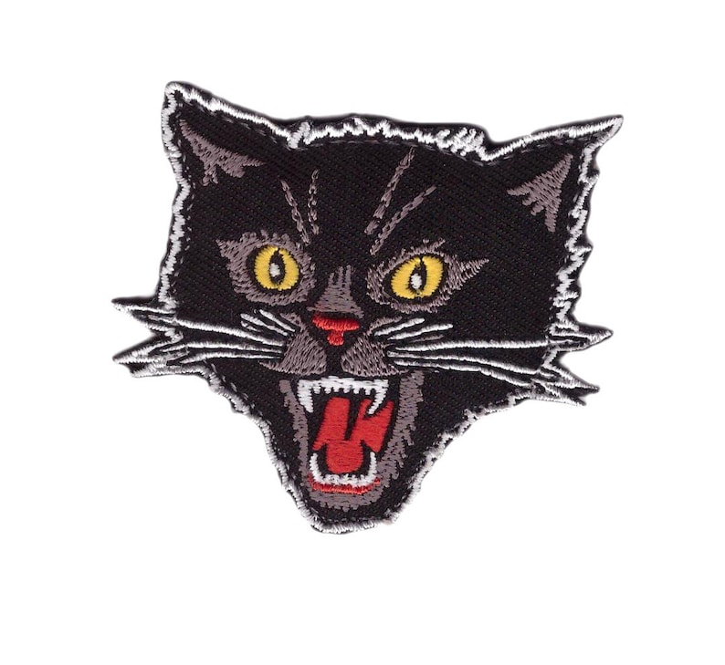 Op de afbeelding: Geborduurde patch met een zwarte kattenkop met een boze uitdrukking. De kat heeft gele ogen, een rode neus en een open mond met tanden en een rode tong. De patch heeft een witte rand.