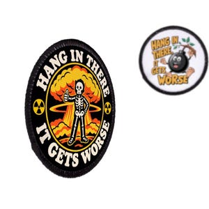 May include: Two circular embroidered patches with black borders. One features a skeleton giving a thumbs up in front of a nuclear explosion with the text HANG IN THERE IT GETS WORSE. The other shows a cartoon bomb hanging from a branch with the same text.