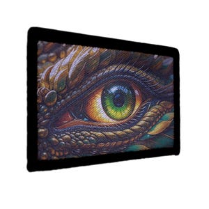 May include: A rectangular image featuring a close-up of a reptilian eye. The eye has a green iris with yellow and orange hues, surrounded by textured scales in shades of brown, gold, and green. The image is framed by a black border.