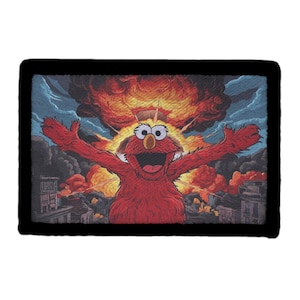 May include: A rectangular patch with a black border featuring a cartoon character with red fur, arms outstretched, against a backdrop of an explosion. The background shows a city engulfed in flames and smoke.