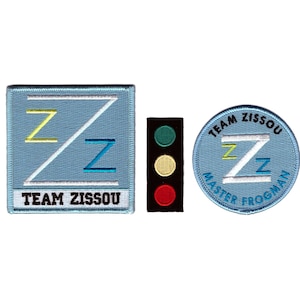 以下が含まれることがあります： 薄い青色の背景に3つの刺繍パッチ。 「TEAM ZISSOU」の文字と様式化された「ZZ」デザインの正方形パッチ。 黒い信号機のパッチ。 「TEAM ZISSOU」と「MASTER FROGMAN」の文字が入った丸いパッチ。