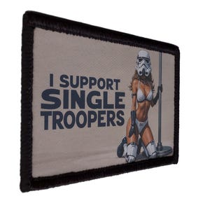 Peut inclure: Écusson rectangulaire à bordure noire avec le texte « I SUPPORT SINGLE TROOPERS ». L'image représente une femme portant un casque de Stormtrooper et un bikini, posant près d'une barre. Le fond est beige clair.