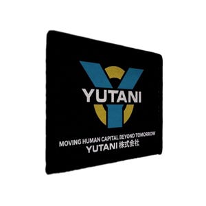 May include: Black rectangular item with the word "YUTANI" in white, with a blue and yellow logo. Below the logo, the text reads "MOVING HUMAN CAPITAL BEYOND TOMORROW" and "YUTANI 株式会社" in white.