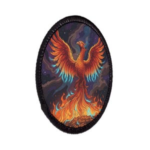 May include: An oval-shaped patch featuring a vibrant phoenix with outstretched wings in shades of orange, red, and yellow. The bird rises from flames against a dark, starry night sky background with swirling purple and blue clouds, all bordered by a black stitched edge.