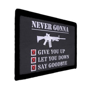 May include: Black rectangular patch with white text and a white rifle graphic. The text reads "NEVER GONNA" above the rifle, and below it, "GIVE YOU UP", "LET YOU DOWN", and "SAY GOODBYE". The patch has a black border.