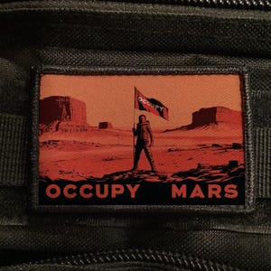 Könnte beinhalten: Ein rechteckiger Aufnäher mit einer roten und orangen Marslandschaft. Eine Figur hält eine Flagge mit der Aufschrift "Occupy". Der Text "Occupy Mars" ist in fetten, schwarzen Buchstaben gedruckt.