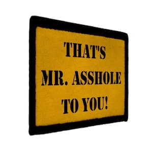May include: A rectangular yellow patch with black text that reads "THAT'S MR. ASSHOLE TO YOU!" The patch has a black border and a textured appearance.