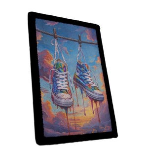 Pode incluir: Um emblema retangular com uma ilustração vibrante de dois ténis de cano alto pendurados num estendal contra um céu ao pôr do sol. Os sapatos parecem derreter-se com gotas coloridas sobre um fundo de nuvens cor de laranja e azuis.