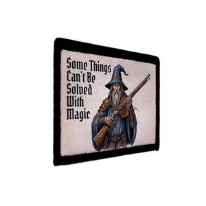 May include: A rectangular wall sign with a black border and a cream-colored background. It features an illustration of a bearded wizard in a blue robe and hat holding a long rifle, with the text Some Things Can't Be Solved With Magic.