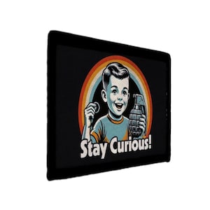 May include: Black rectangular graphic with a retro illustration of a smiling boy holding a grenade and a coin. A rainbow arch is behind the boy. The text "Stay Curious!" is below the boy.