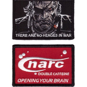 May include: Two rectangular patches. The top patch is black with a detailed grey and white illustration of a bearded man smoking a cigar, with the text "THERE ARE NO HEROES IN WAR". The bottom patch is red with white text that reads "narc DOUBLE CAFFEINE OPENING YOUR BRAIN".