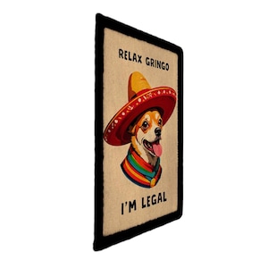 May include: A rectangular graphic featuring a dog wearing a sombrero and a colorful scarf. The text "RELAX GRINGO" is at the top, and "I'M LEGAL" is at the bottom. The dog has its tongue out.