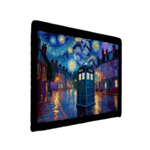 Könnte beinhalten: Ein gerahmter Kunstdruck, der eine blaue Polizeibox auf einer Kopfsteinpflasterstraße unter einem Sternenhimmel zeigt. Das Kunstwerk weist eine lebendige Farbpalette mit Blau-, Gelb- und Lilatönen auf, die an einen berühmten Malstil erinnert. Die Worte "POLICE" sind auf der Box zu sehen.