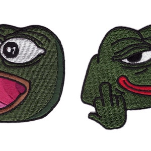 Könnte beinhalten: Zwei gestickte Aufnäher mit einer grünen Froschfigur. Ein Aufnäher zeigt den Frosch mit weit aufgerissenen Augen und offenem Mund, der andere zeigt den Frosch mit erhobenem Mittelfinger. Die Aufnäher haben einen weißen Hintergrund.