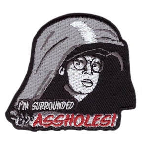 Könnte beinhalten: Gestickter Aufnäher mit einem Cartoon-Bild einer Person mit Brille und Kapuze, mit dem Text "I'M SURROUNDED BY ASSHOLES!" in weißen und roten Buchstaben. Der Aufnäher hat einen schwarzen Rand und ist für Kleidung oder Accessoires bestimmt.