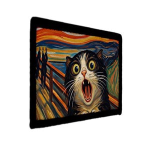 May include: A rectangular black framed print featuring a cat with wide eyes and an open mouth, mimicking the style of Edvard Munch's "The Scream" painting. The background depicts a colorful, swirling landscape.