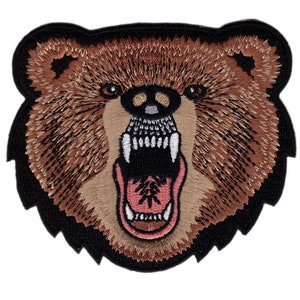 May include: Embroidered patch featuring a roaring bear's head. The bear has brown fur, a black outline, and a detailed open mouth with visible teeth and a pink tongue. The patch is designed for application on clothing or accessories.
